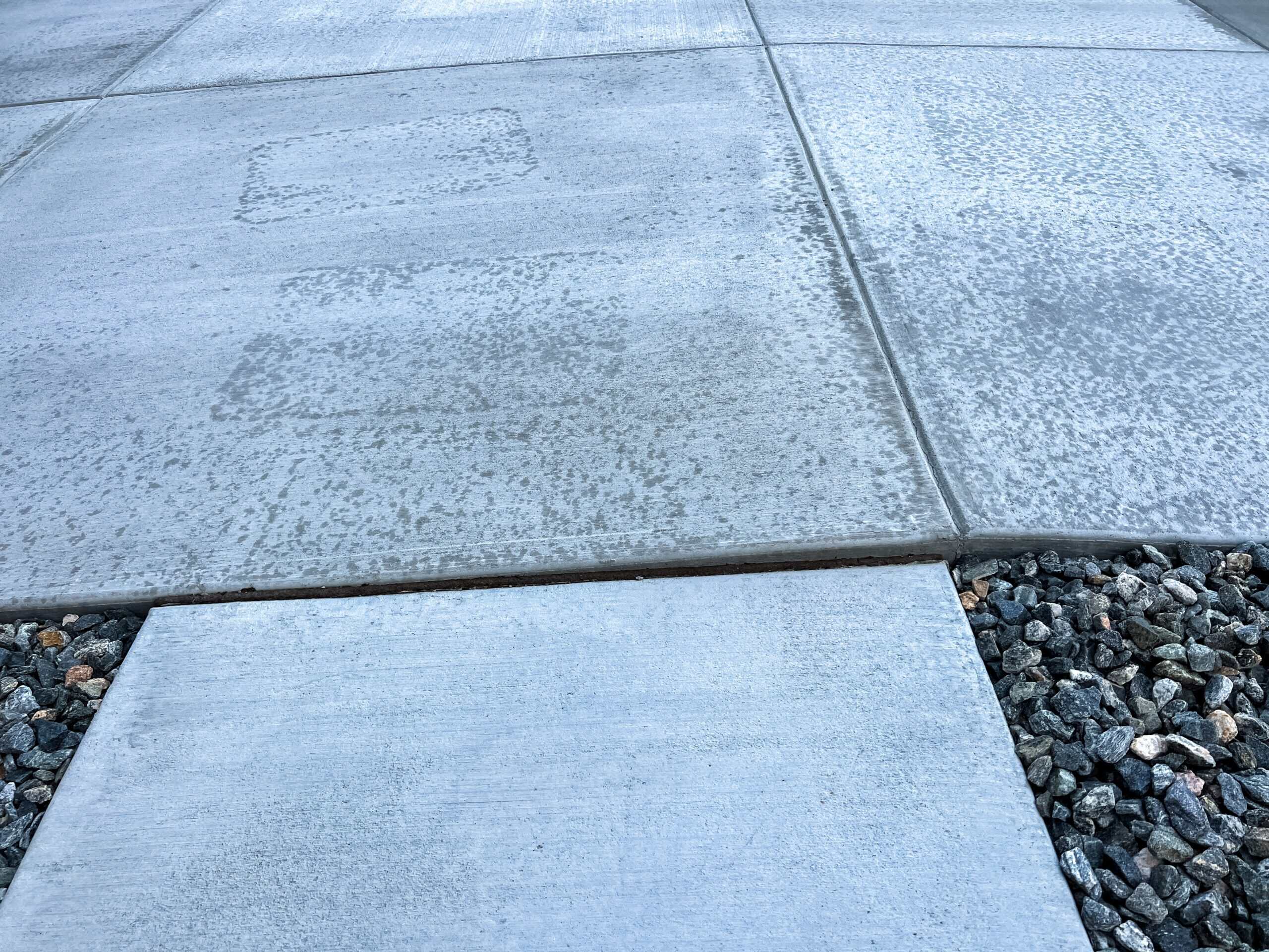 Large square concrete pavers separated by sections of loose gravel, showing areas that could benefit from polyurethane concrete lifting.